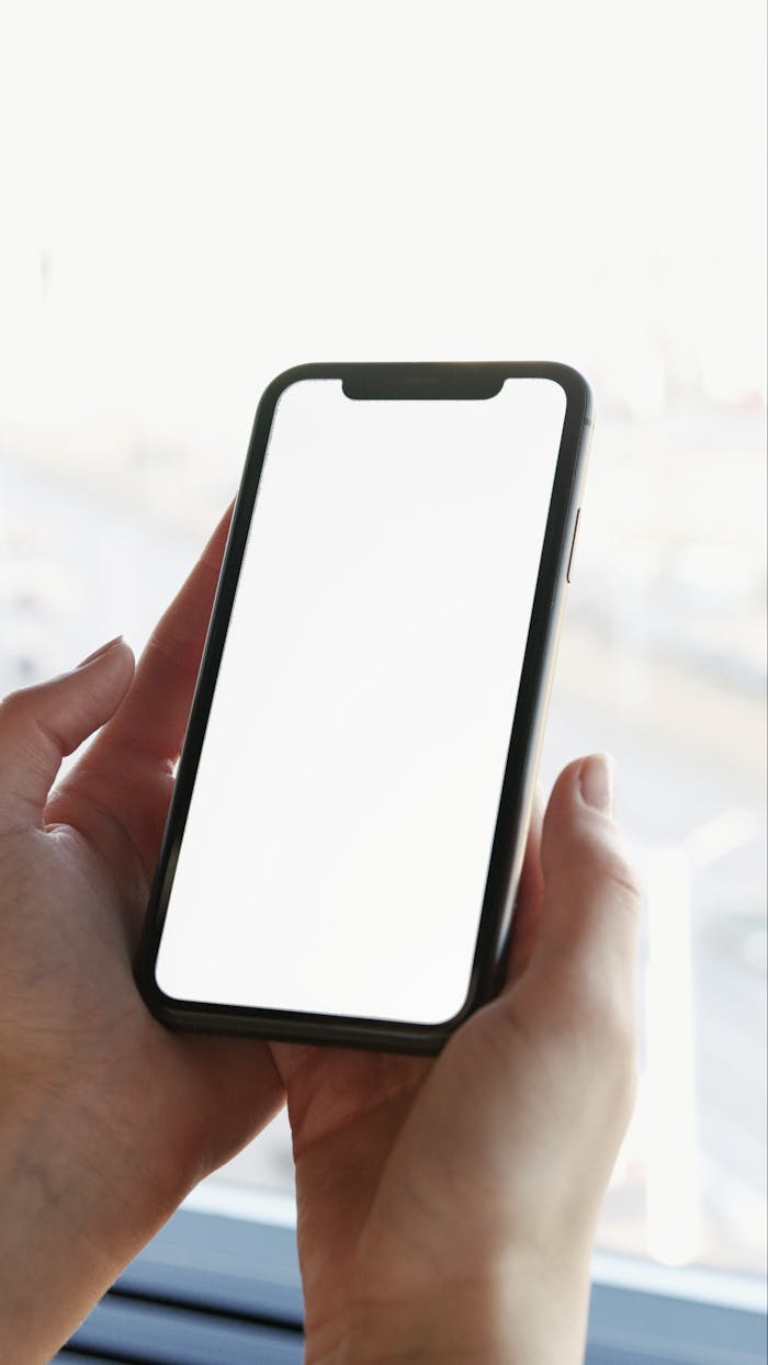services-02 A close-up shot of hands holding a smartphone with a blank screen for mockup usage.