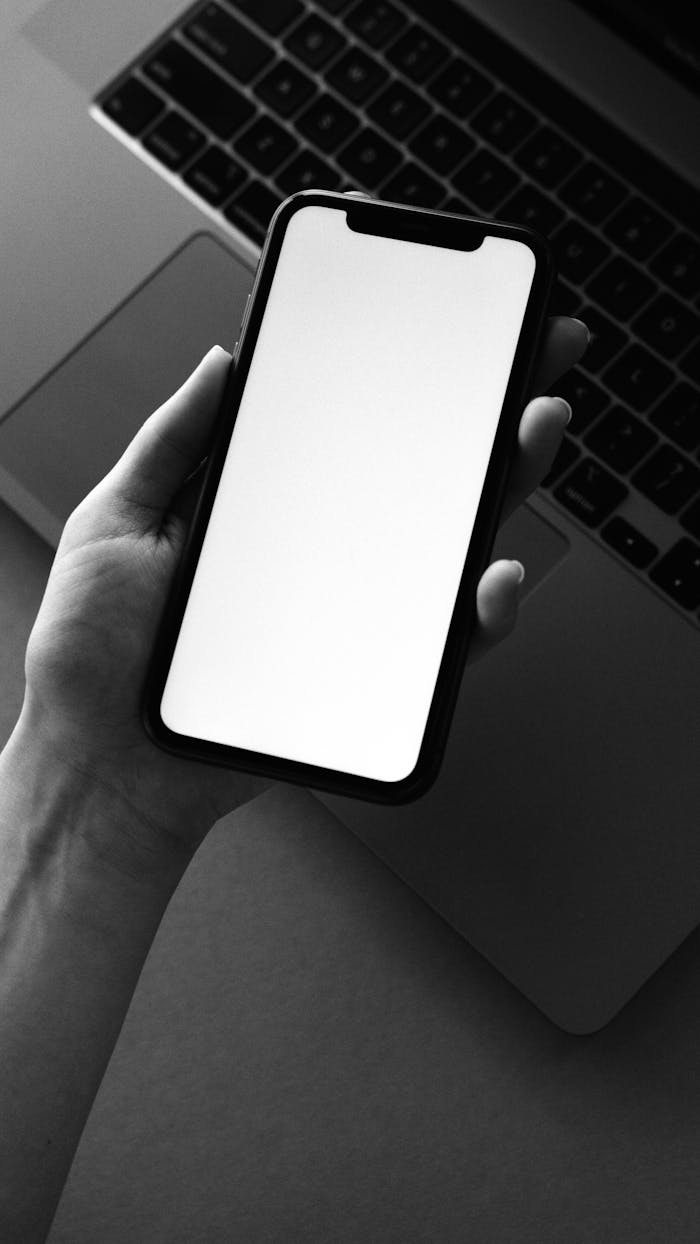 services-01 Monochrome photo of a smartphone held over a laptop for tech-themed design.